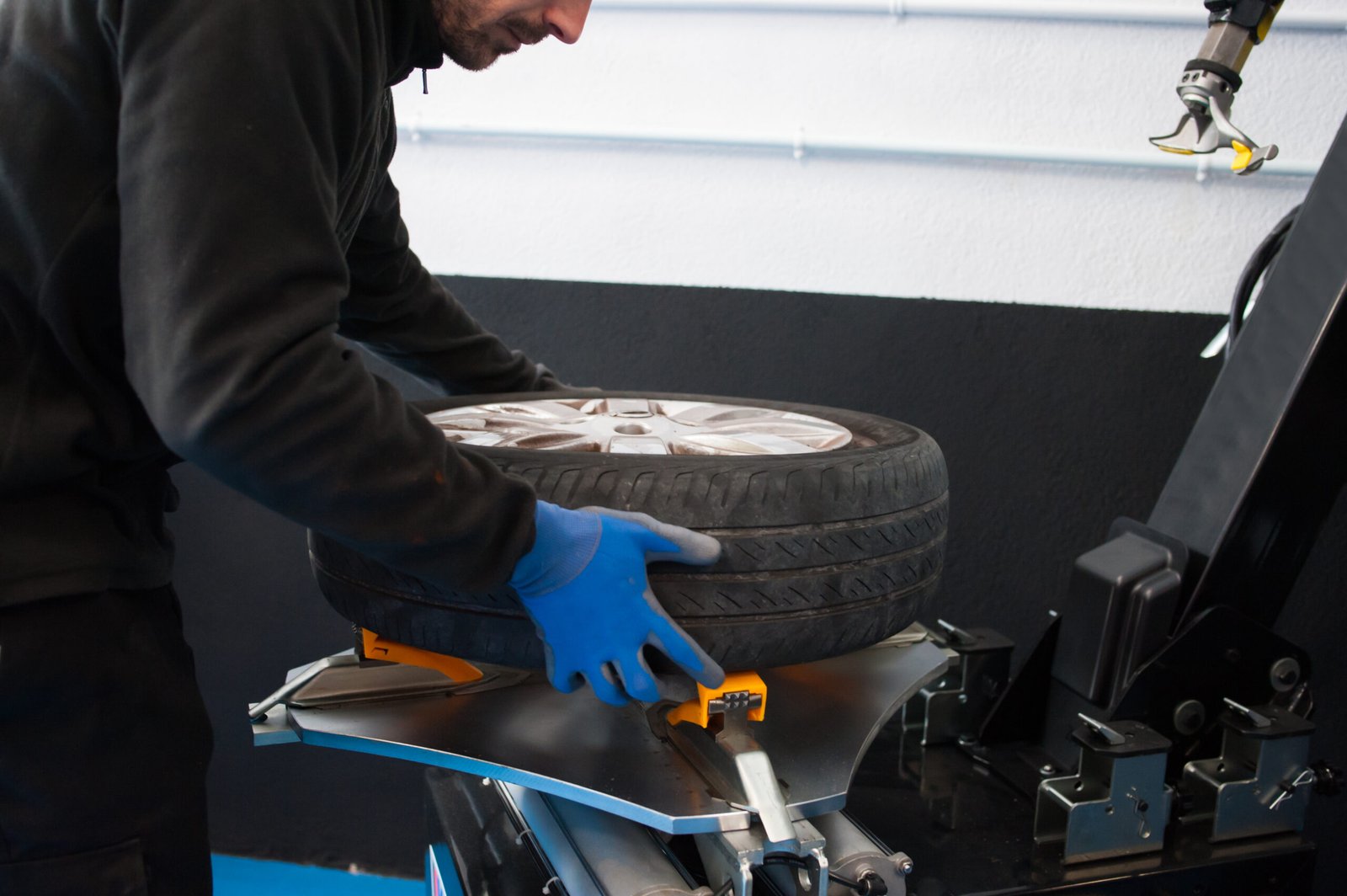 midsection-male-mechanic-holding-tire-auto-repair-shop